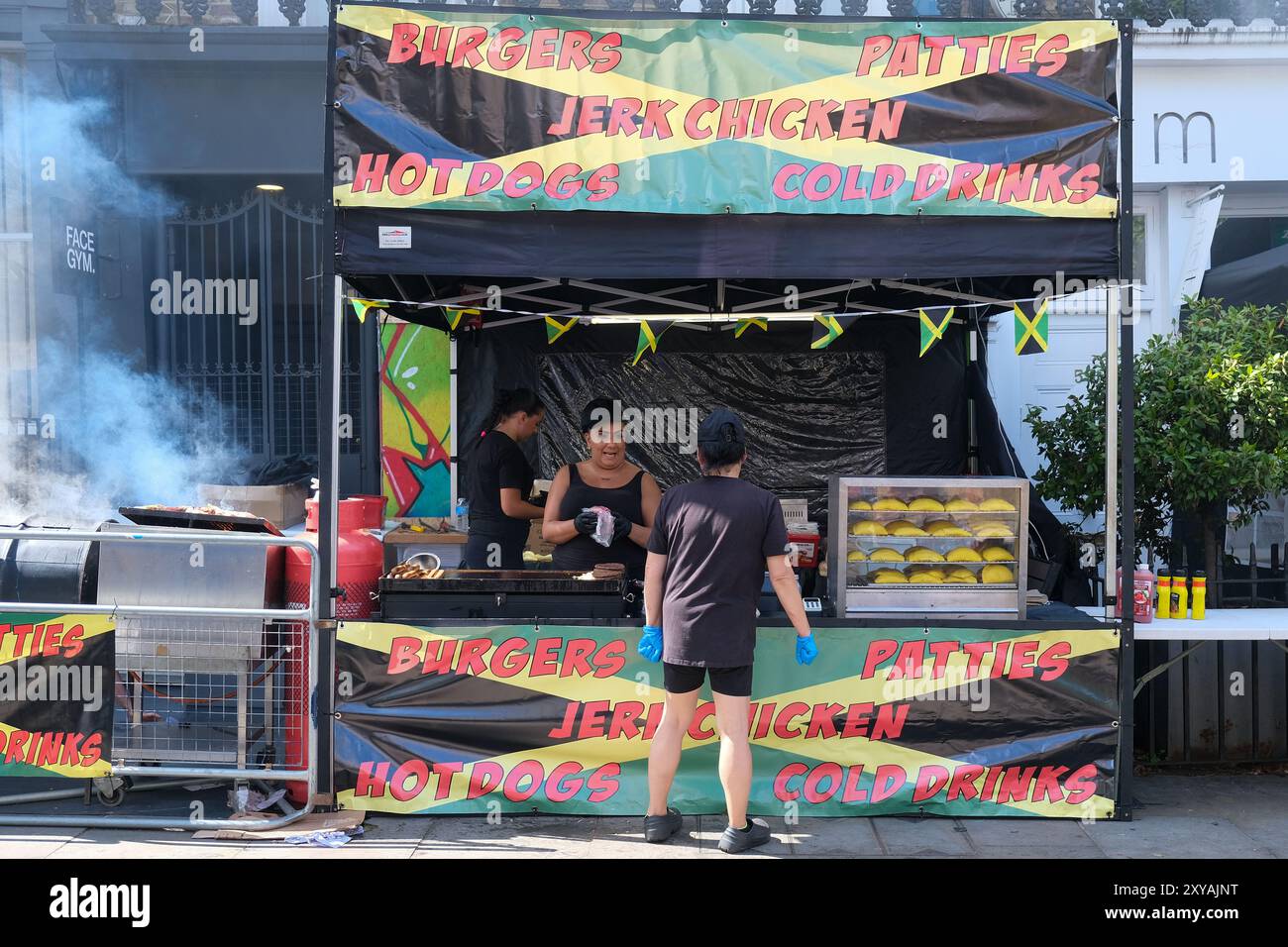 Londra, Regno Unito. Le bancarelle fiancheggiano il percorso del Carnevale di Notting Hill, che offre un'appetitosa scorta di pollo strapazzato, acqua di cocco, punch al rum e molto altro. Foto Stock