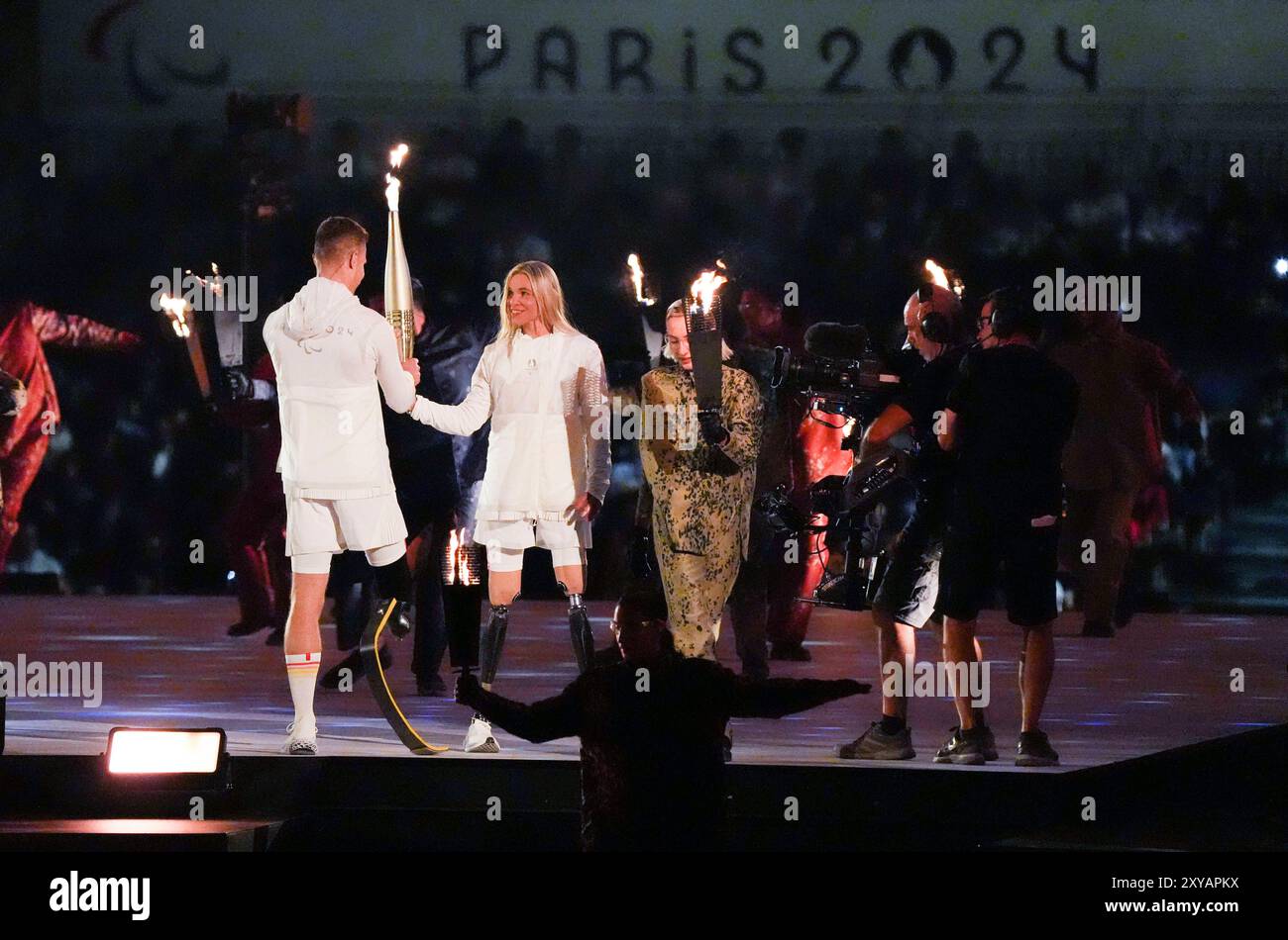 Parigi, Francia. 28 agosto 2024. I portatori di torce Oksana Masters (2° L) degli Stati Uniti e Markus Rehm (1° L) della Germania tengono la fiamma durante la cerimonia di apertura dei Giochi Paralimpici di Parigi 2024 a Parigi, Francia, 28 agosto 2024. Crediti: Xing Guangli/Xinhua/Alamy Live News Foto Stock