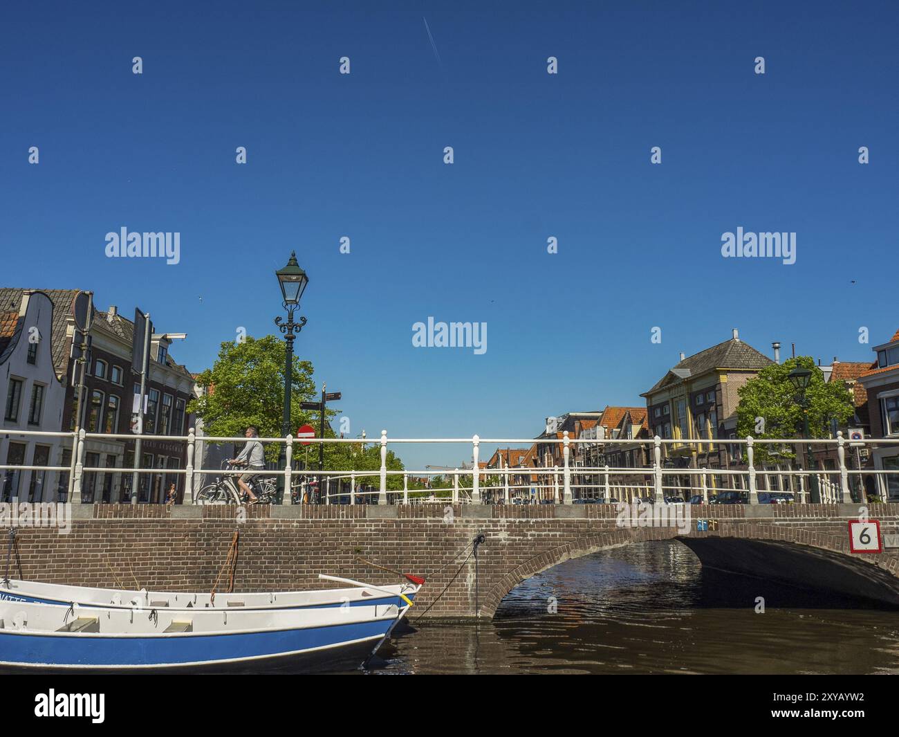 Scena dipinta di un ponte su un fiume tranquillo con barche e vecchi edifici sotto un cielo azzurro, alkmaar, paesi bassi Foto Stock
