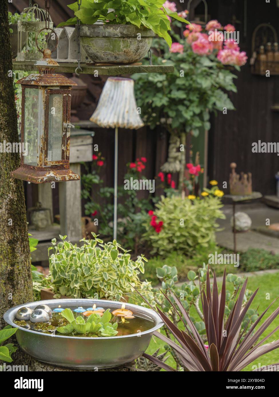 Giardino con varie piante ed elementi decorativi, tra cui rose e una lampada a sospensione, borken, muensterland, germania Foto Stock