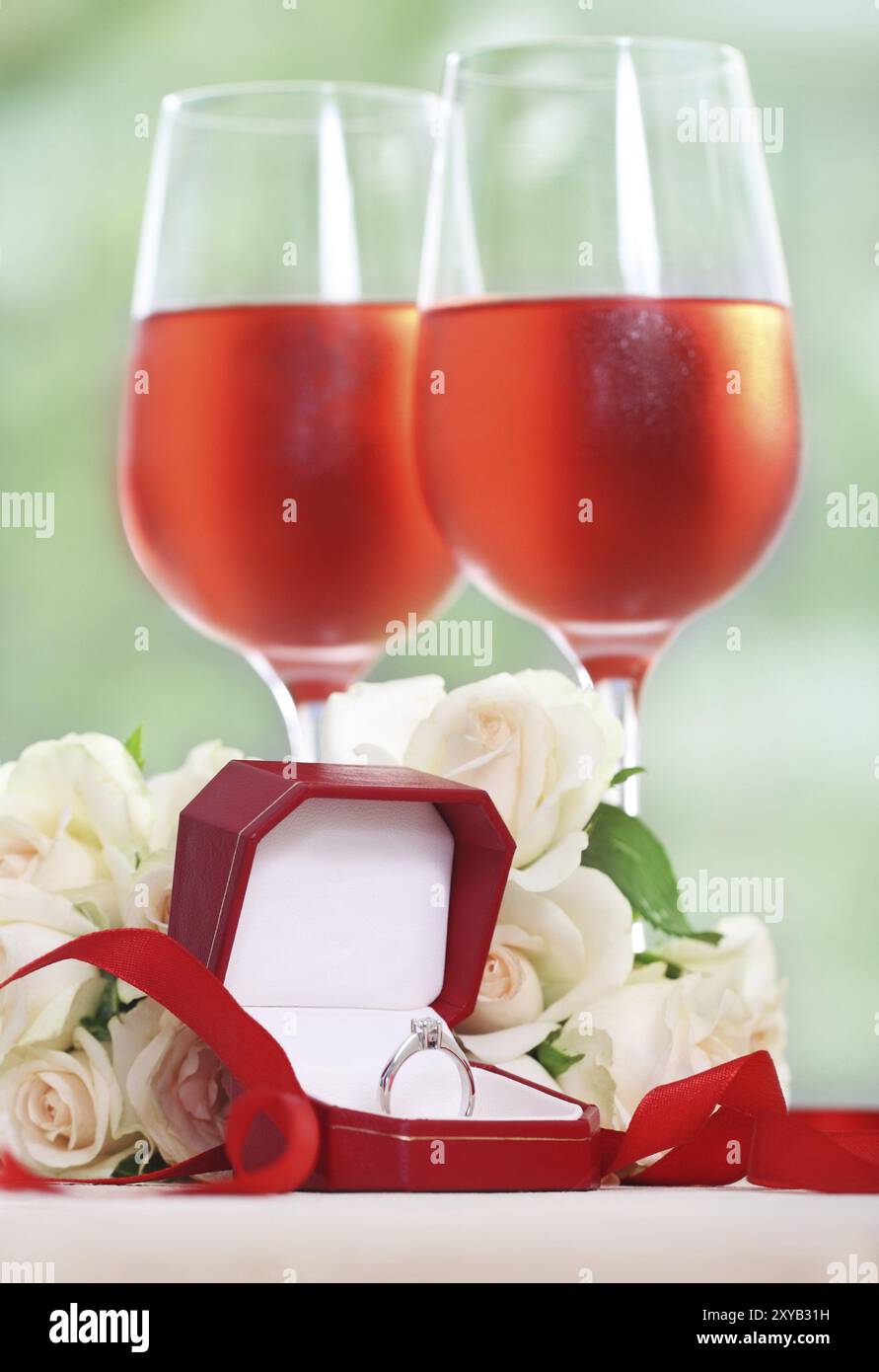 Proposta di matrimonio. Un impegno corona diamantata nella casella con rose e vino rosato Foto Stock