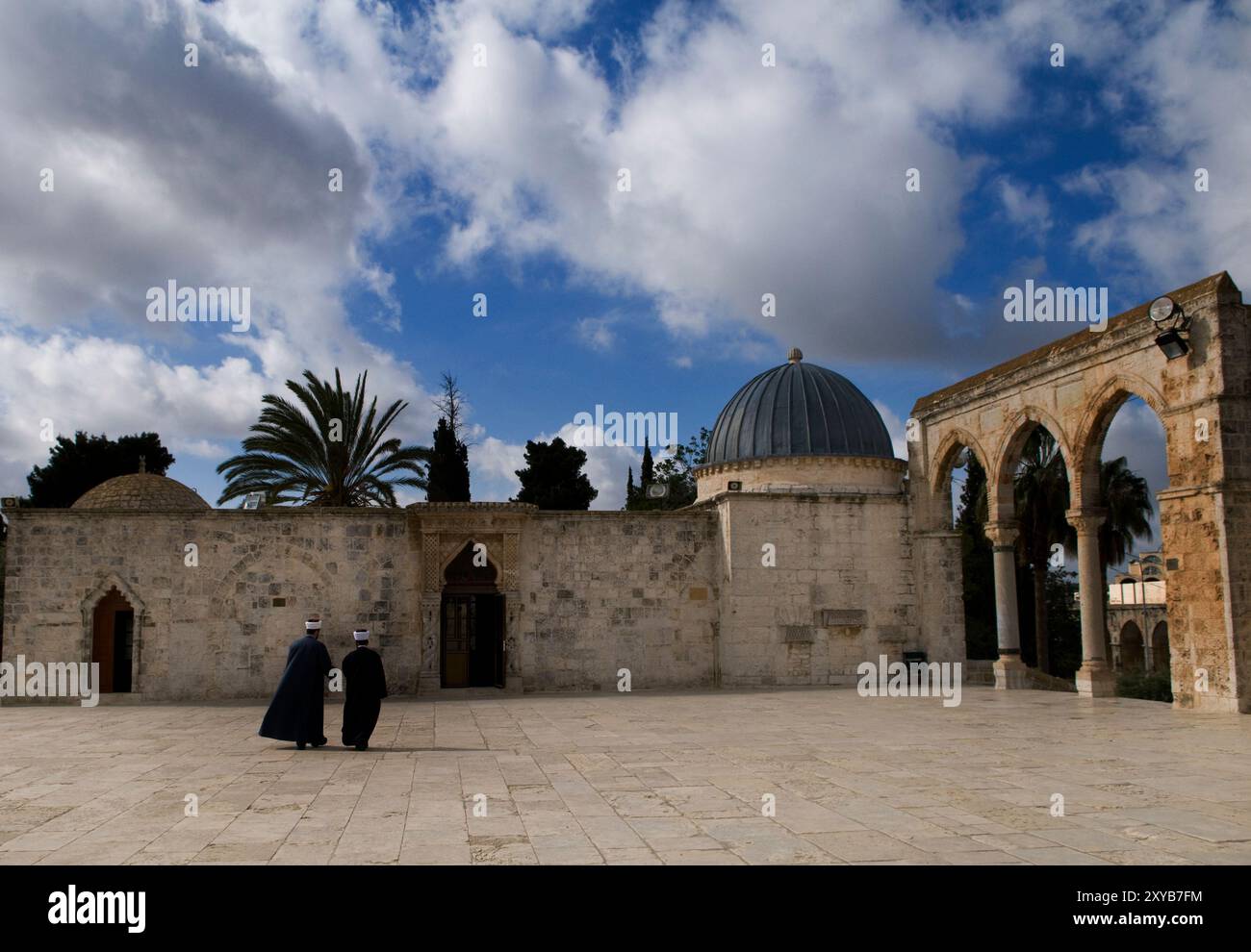 Imam che cammina nel cortile accanto alla moschea al-Aqsa, al Monte del Tempio e alla città vecchia di Gerusalemme. Foto Stock
