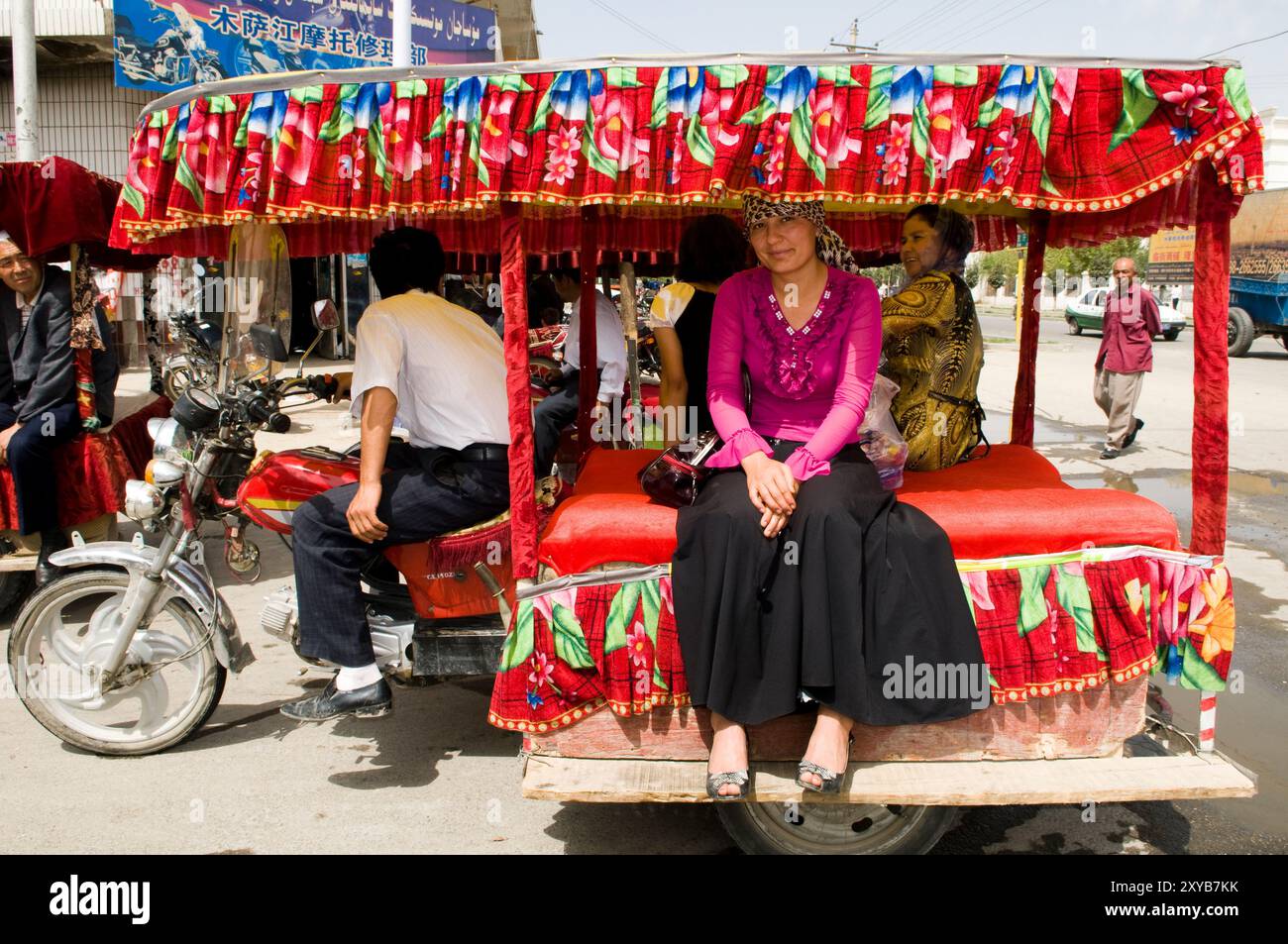 Donne uigure sedute su un taxi per moto locale nella periferia di Kashgar, Xinjiang, Cina. Foto Stock