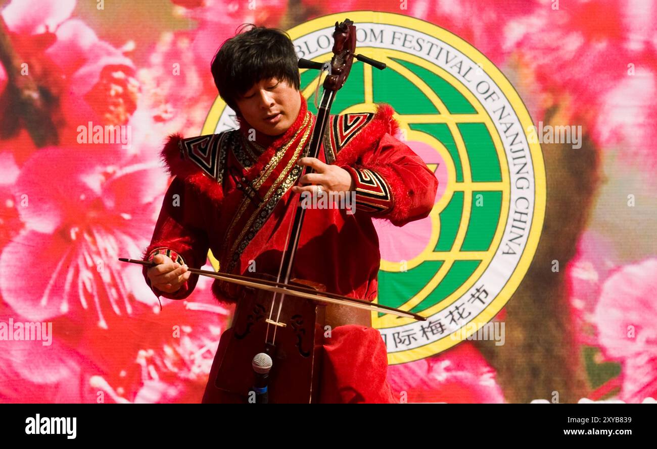 Musicista mongolo che suona il morin khuur, uno strumento a due corde durante il Blossom festival a Nanchino, in Cina. Foto Stock