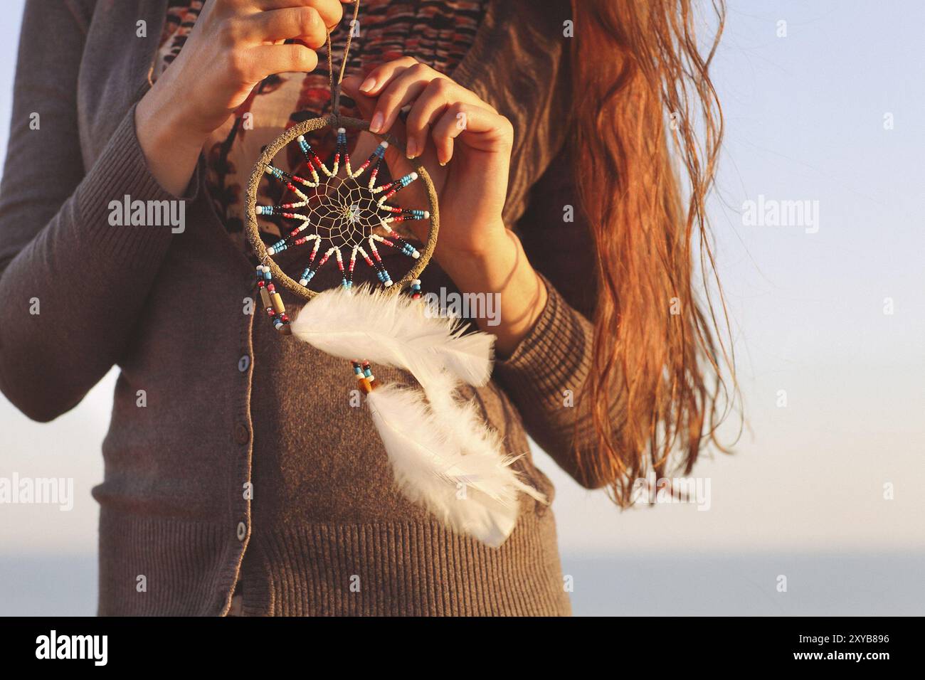 Brunette donna con capelli lunghi tenendo dream catcher nelle sue mani Foto Stock
