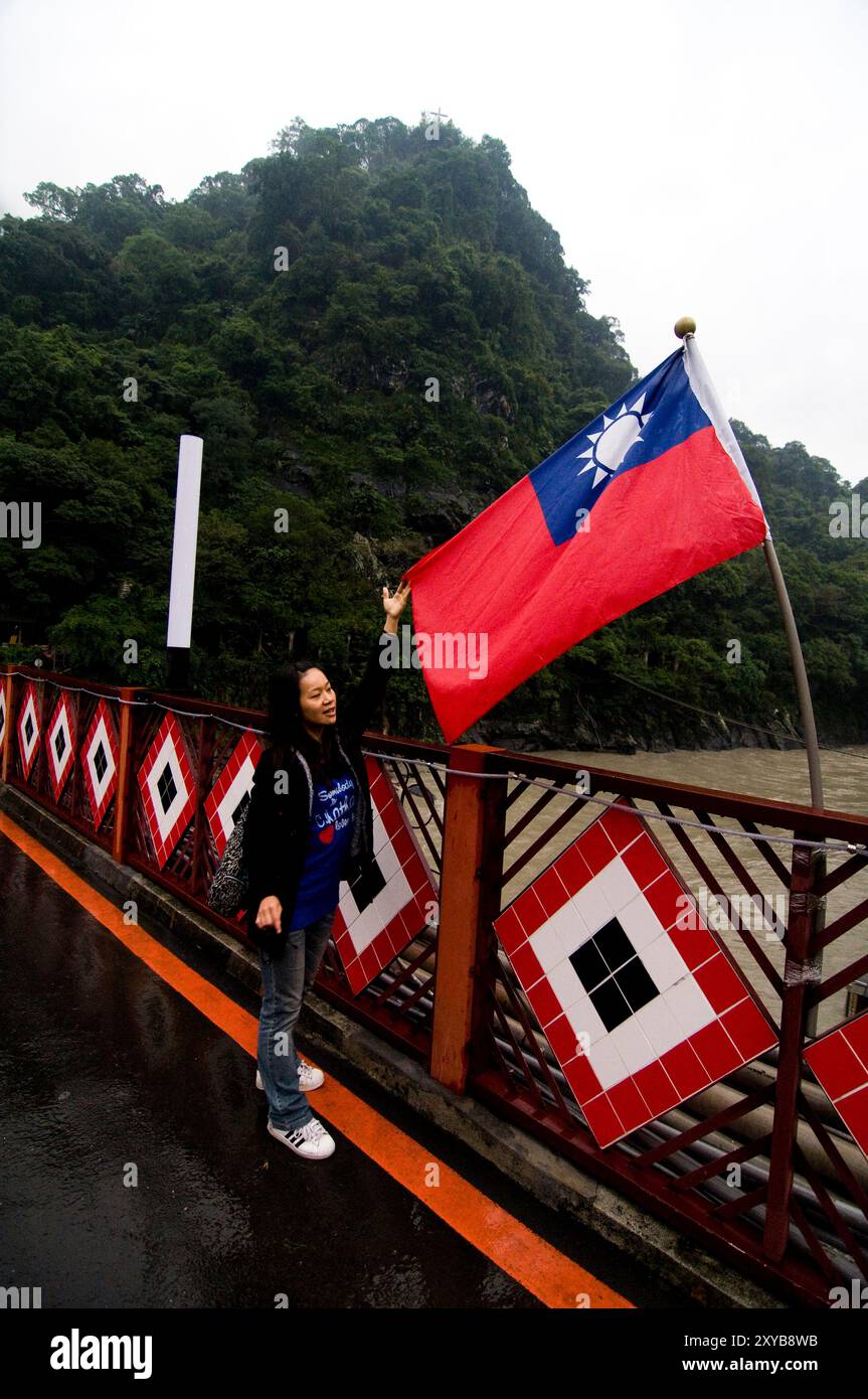 Una donna taiwanese in piedi accanto alla bandiera di Taiwan. Foto Stock