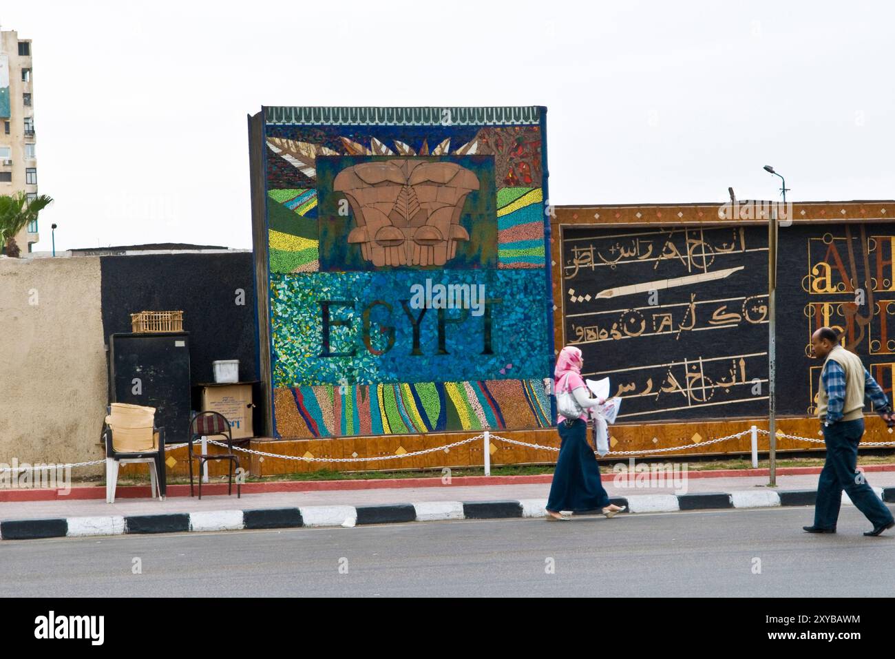 Studenti universitari egiziani che camminano accanto a un muro decorato con colori ad Alessandria, in Egitto. Foto Stock