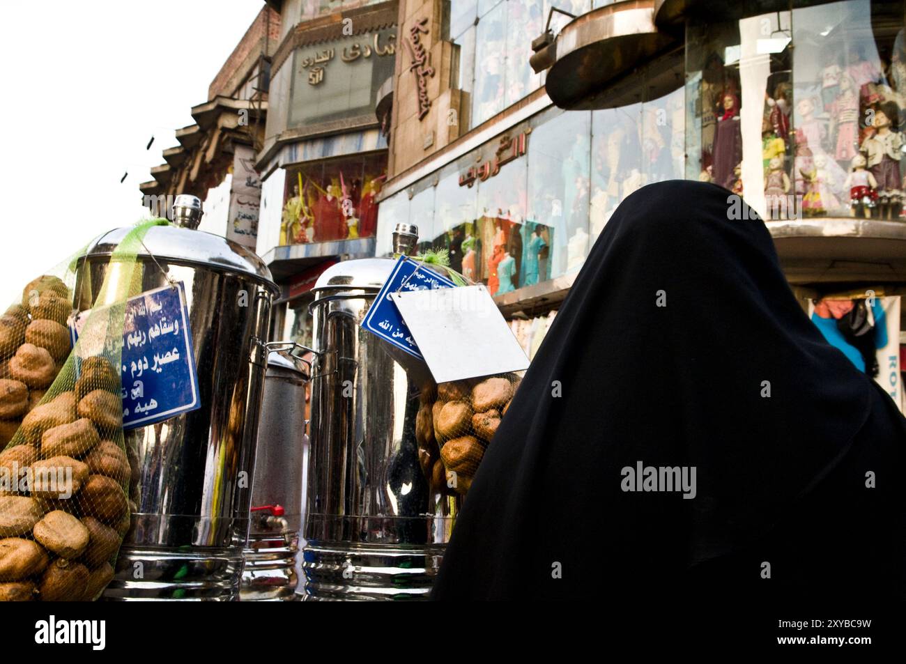 Una donna egiziana accanto a un venditore di succo di tamarindo al mercato Khal El Khalili del Cairo, in Egitto. Foto Stock