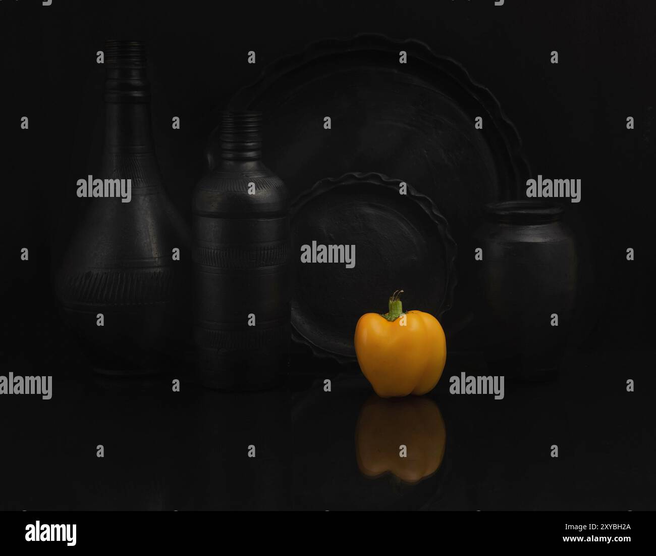 STILL Life con piattino nero e piatti con un peperone. Primo piano, ripresa in studio. Foto Stock