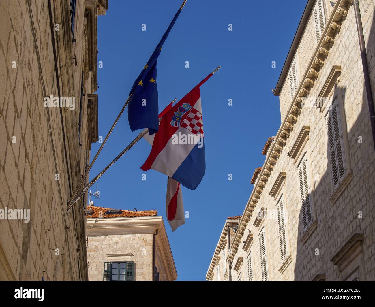 Bandiera UE e bandiera croata tra edifici storici sotto un cielo blu, Dubrovnik, Mar Mediterraneo, Croazia, Europa Foto Stock