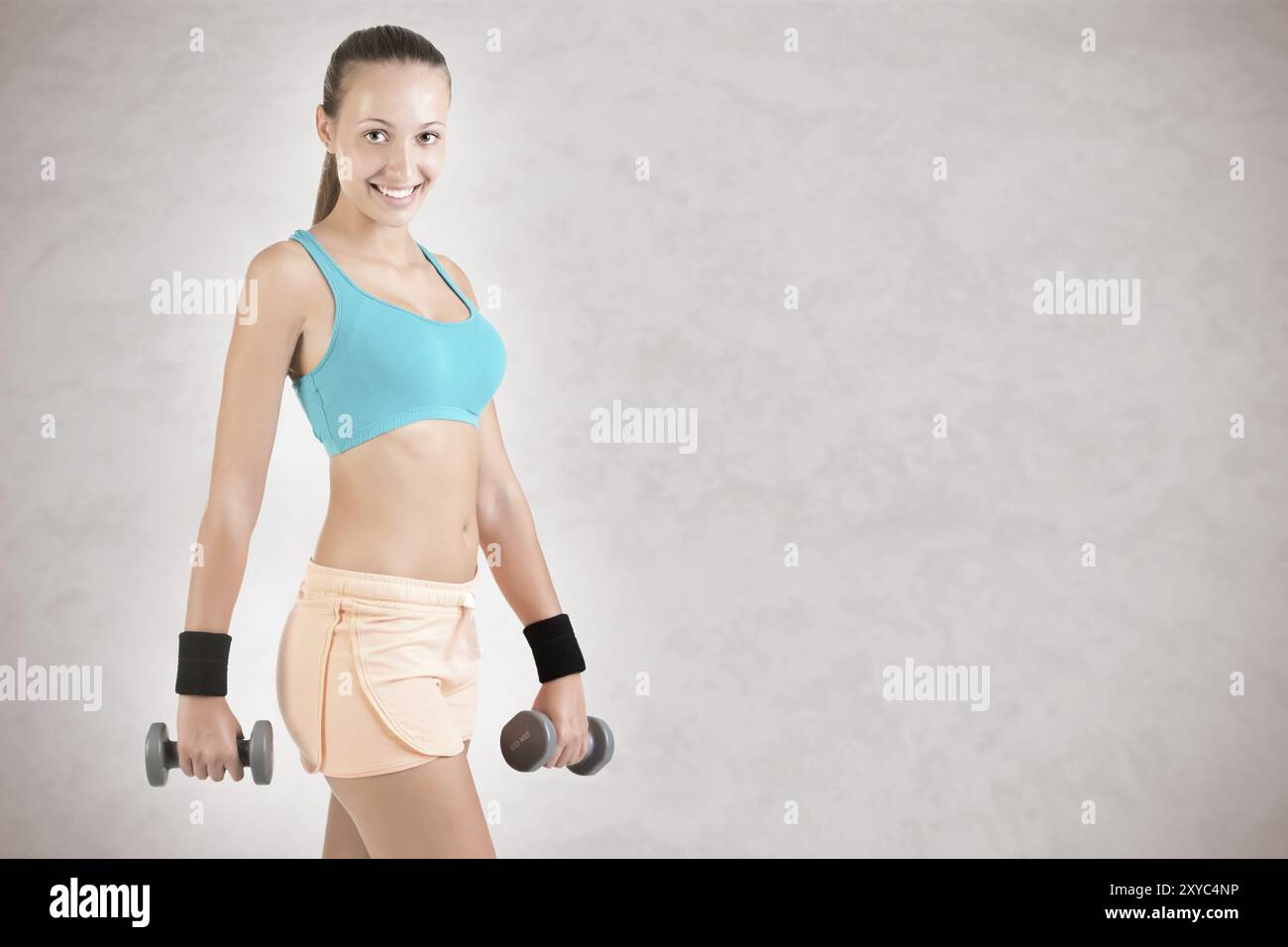 La donna che lavora fuori con manubri in grigio Foto Stock