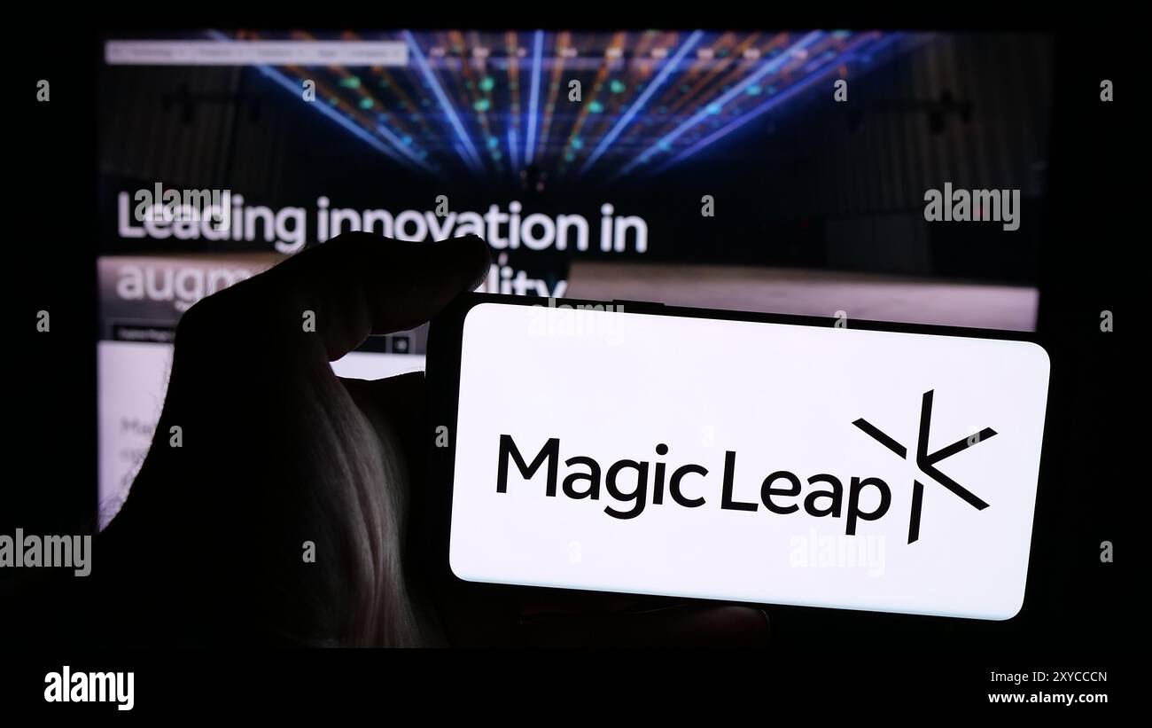Persona che possiede uno smartphone con il logo della società statunitense di visualizzazione di realtà aumentata Magic Leap Inc. Davanti al sito Web. Mettere a fuoco il display del telefono. Foto Stock