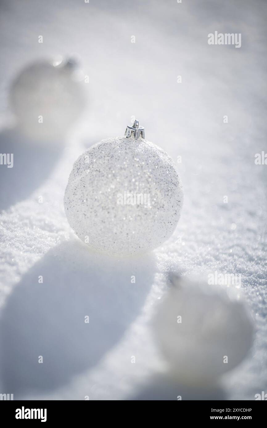 Palle di Natale d'argento sulla neve vera all'aperto. Concetto di vacanza invernale. Profondità bassa dei campi Foto Stock