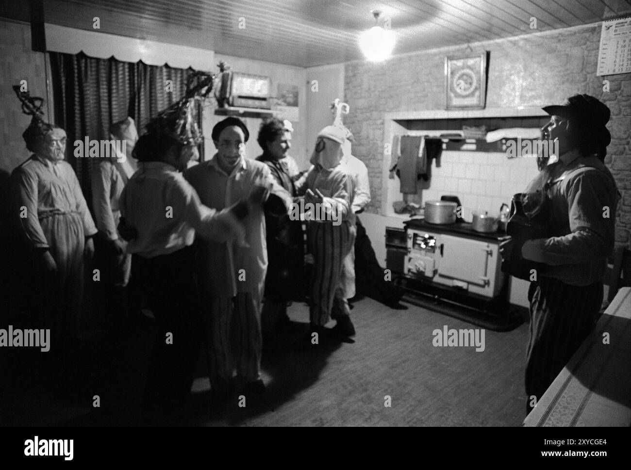 Irlanda rurale anni '1970 Festival folcloristico annuale dei Biddy Boys che celebra il Santo celtico, St Brigit o St Brigid. I suoi santi festeggiano il giorno in cui i Biddy Boys vanno di casa in casa, visitando vicini e fattorie periferiche. Dove si svolgono musica e balli. La signora del centro della casa balla con un Biddy Boy. Tutti si trovano nella camera principale al piano inferiore, usata come cucina e zona soggiorno. Killorglin, Contea di Kerry, Irlanda del Sud febbraio 1972 1970s Eire HOMER SYKES Foto Stock