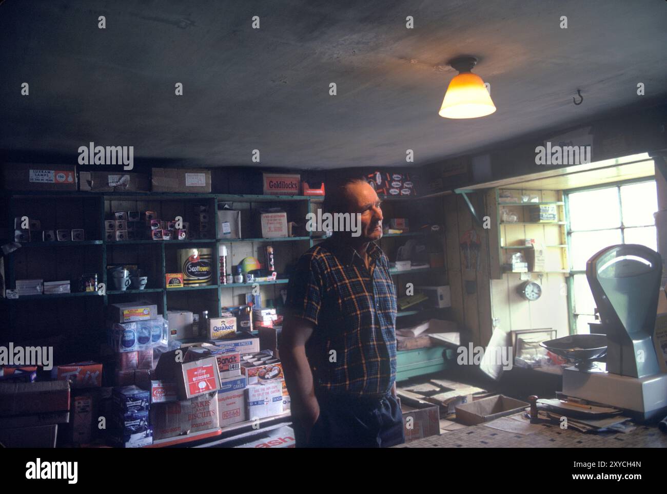 Negozio interno in vecchio stile. Un negoziante dietro il bancone del suo negozio di generi. Shetlands Mainland, Isole Shetland, Scozia 1979. UK 1970S HOMER SYKES Foto Stock