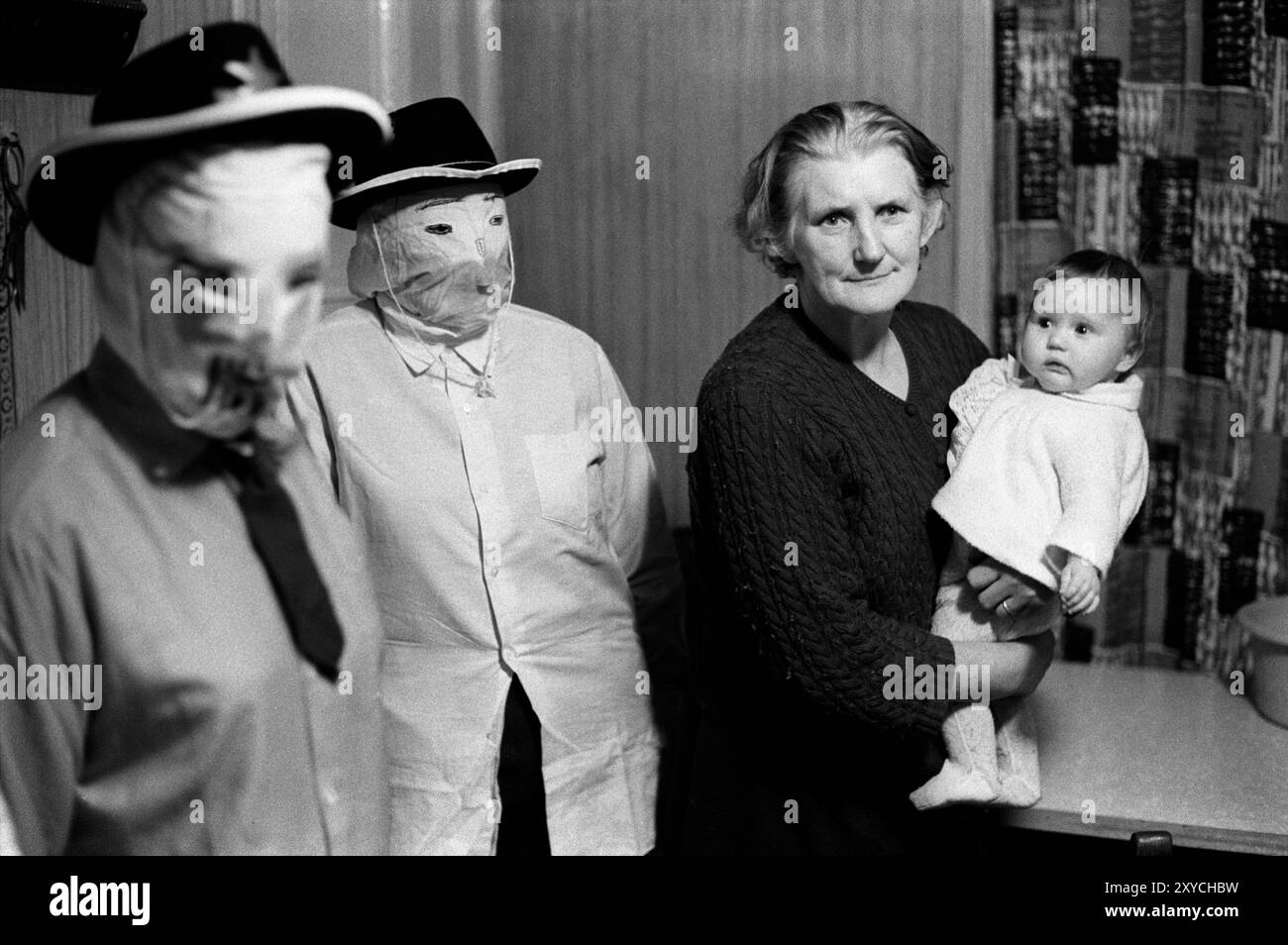 Folklore irlandese. Biddy Boys, tradizionale festa annuale del folclore irlandese. Una festa per celebrare il Santo celtico, St Brigit o St Brigid. Due Biddy Boys in maschera, nonna con un nipote spaventato, stanno guardando la danza tradizionale. Killorglin, Contea di Kerry, Irlanda del Sud febbraio 1972 1970s Eire HOMER SYKES Foto Stock