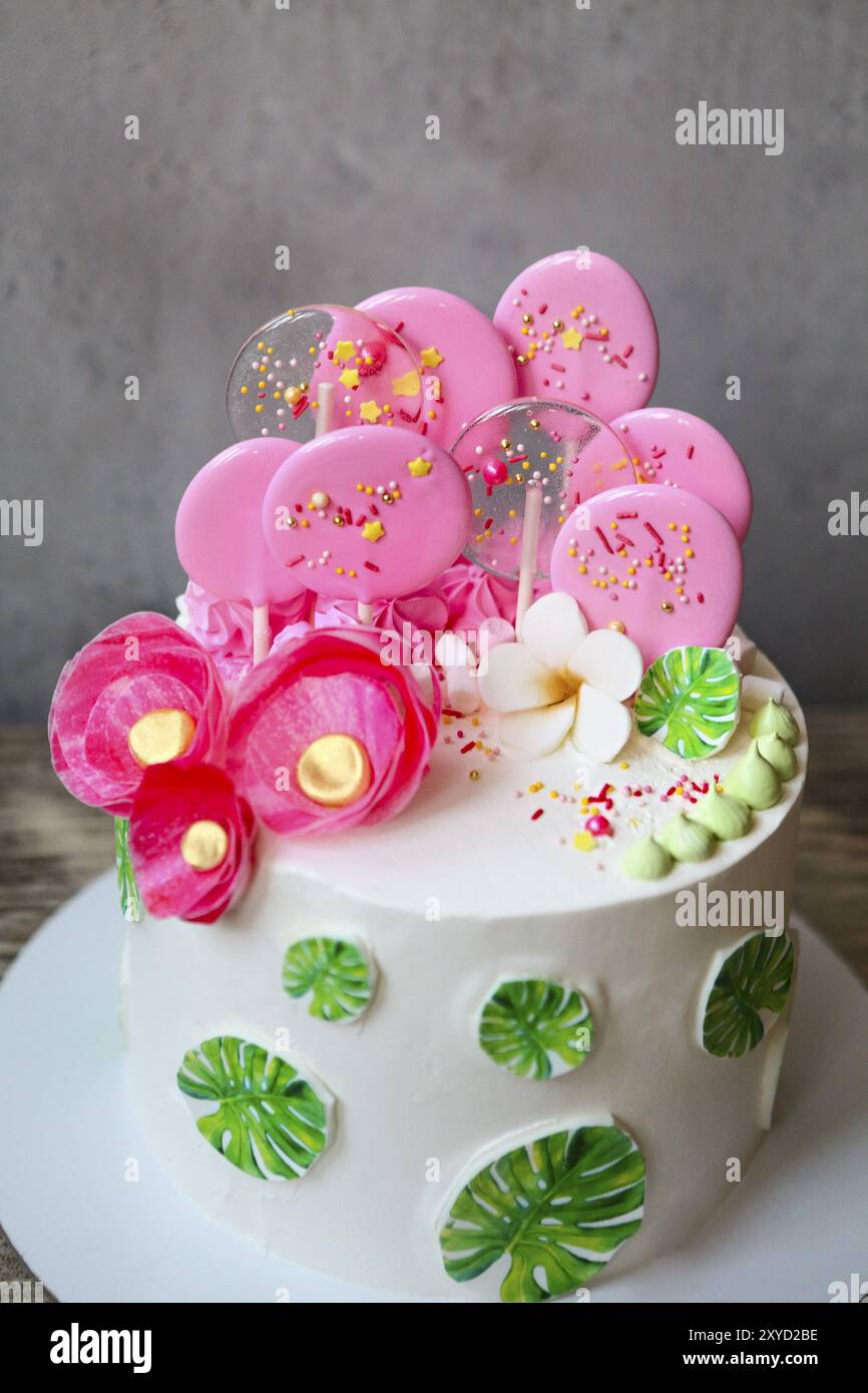 Torta natalizia con foglie di mostera. Ispirazione per una festa di compleanno tropicale. Gustosa torta con fiori di carta wafer e caramelle al caramello Foto Stock