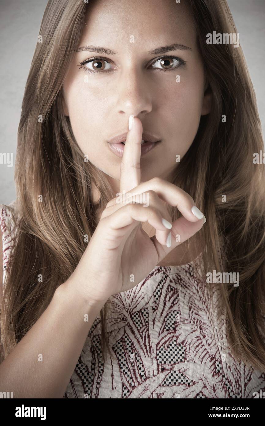 Primo piano di una donna con il suo dito sopra la sua bocca in un umore scuro Foto Stock