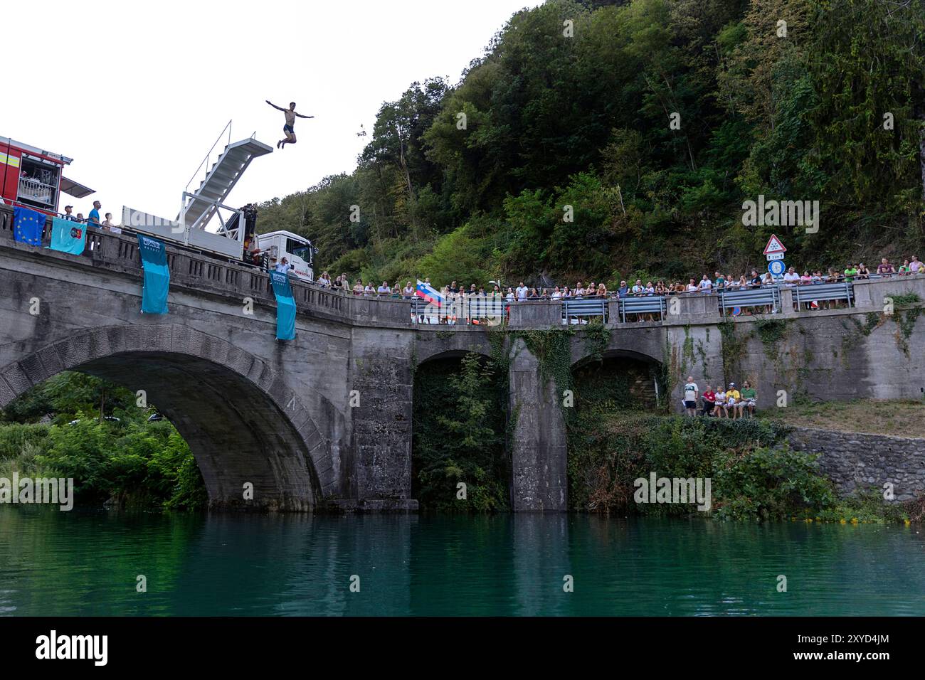 Evento tradizionale di salto dal ponte con un tuffatore che salta dal ponte storico alto di Most na Soci, Slovenia, nel fiume smeraldo. Foto Stock
