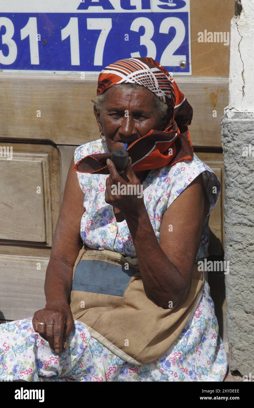 Una vecchia che fuma una pipa sul ciglio della strada, Mindelo, Capo Verde, Africa Foto Stock