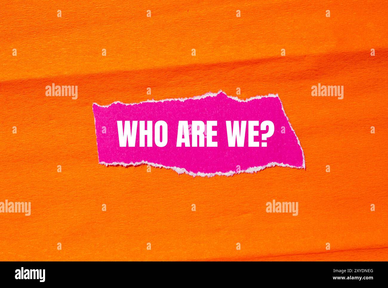 Chi siamo, messaggio di interrogazione scritto su carta rosa strappata con sfondo arancione. Conceptual We We Question Symbol. Copia spazio. Foto Stock