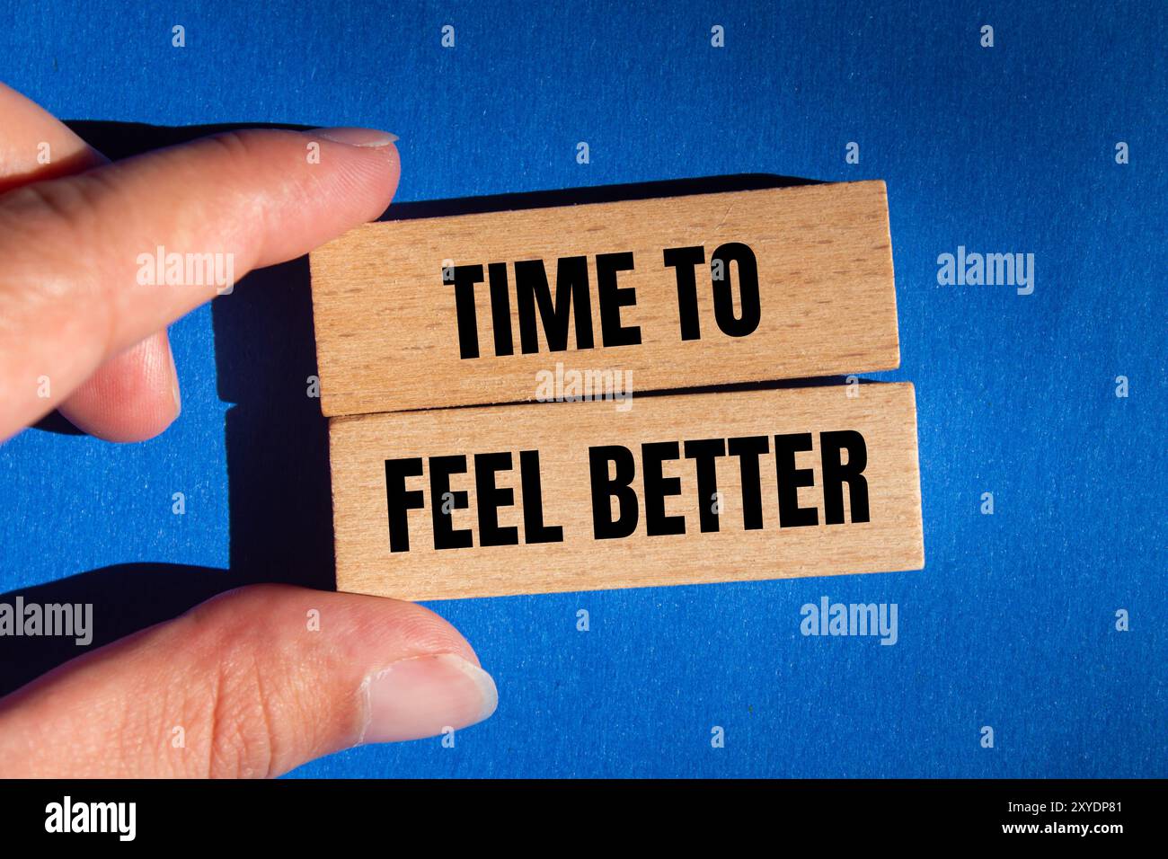 Tempo per sentirsi meglio messaggio scritto su blocchi di legno con sfondo blu. Simbolo tempo concettuale per sentirsi meglio. Copia spazio. Foto Stock