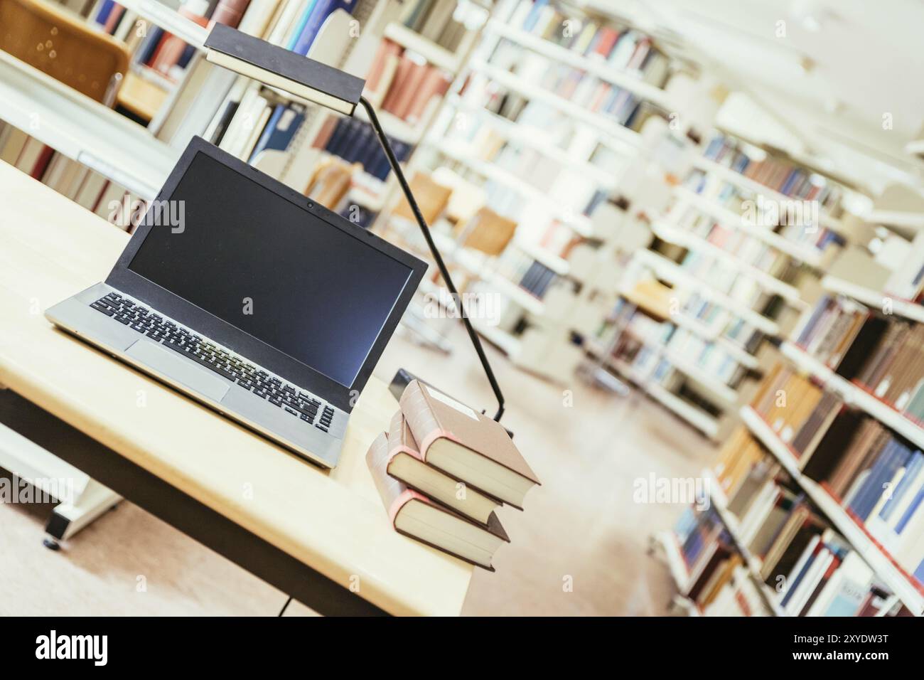 Laptop e una pila di libri su un tavolo di legno. Biblioteca universitaria Foto Stock