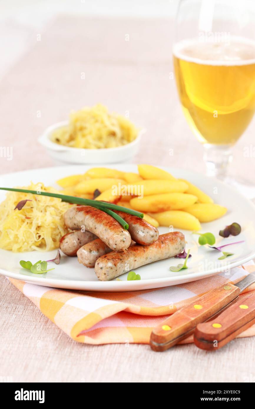 Tradizionale piatto tedesco di salsiccia di vitello con crauti e involtini di spaghetti con birra Foto Stock