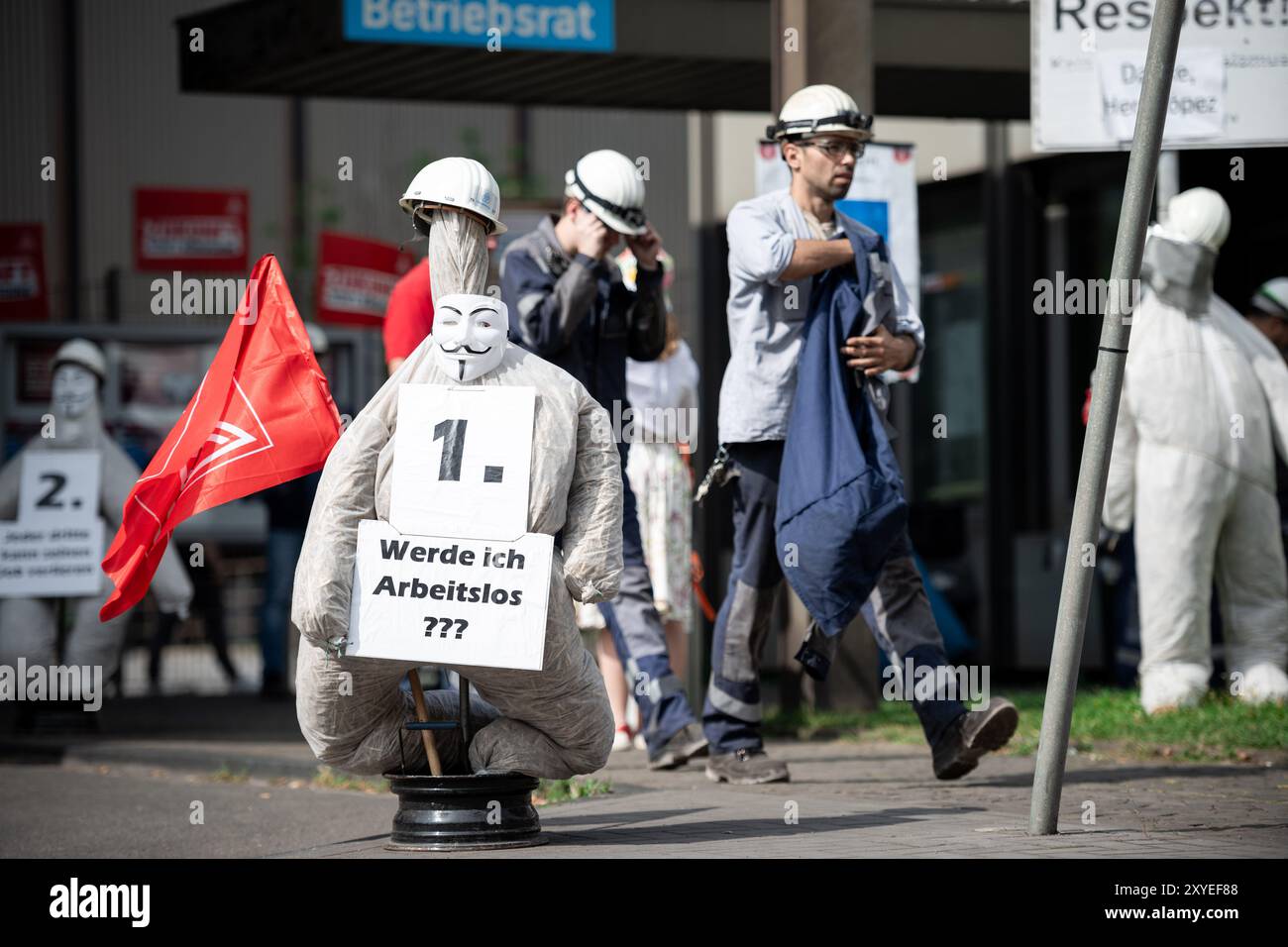 Duisburg, Germania. 29 agosto 2024. I lavoratori passano accanto a una figura che simboleggia un operaio siderurgico con le parole "sarò disoccupato??" Durante la riunione del Consiglio di vigilanza a ThyssenKrupp Steel Europe. Riunione del Consiglio di vigilanza alla ThyssenKrupp Steel Europe in Germania. Secondo le informazioni fornite da diversi organi di informazione, uno degli argomenti da discutere è la risoluzione dei contratti di diversi membri del Consiglio di divisione. Crediti: Fabian Strauch/dpa/Alamy Live News Foto Stock