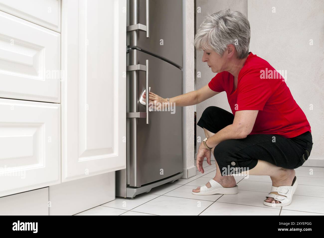 La donna sta in cucina e pulisce il frigo Foto Stock