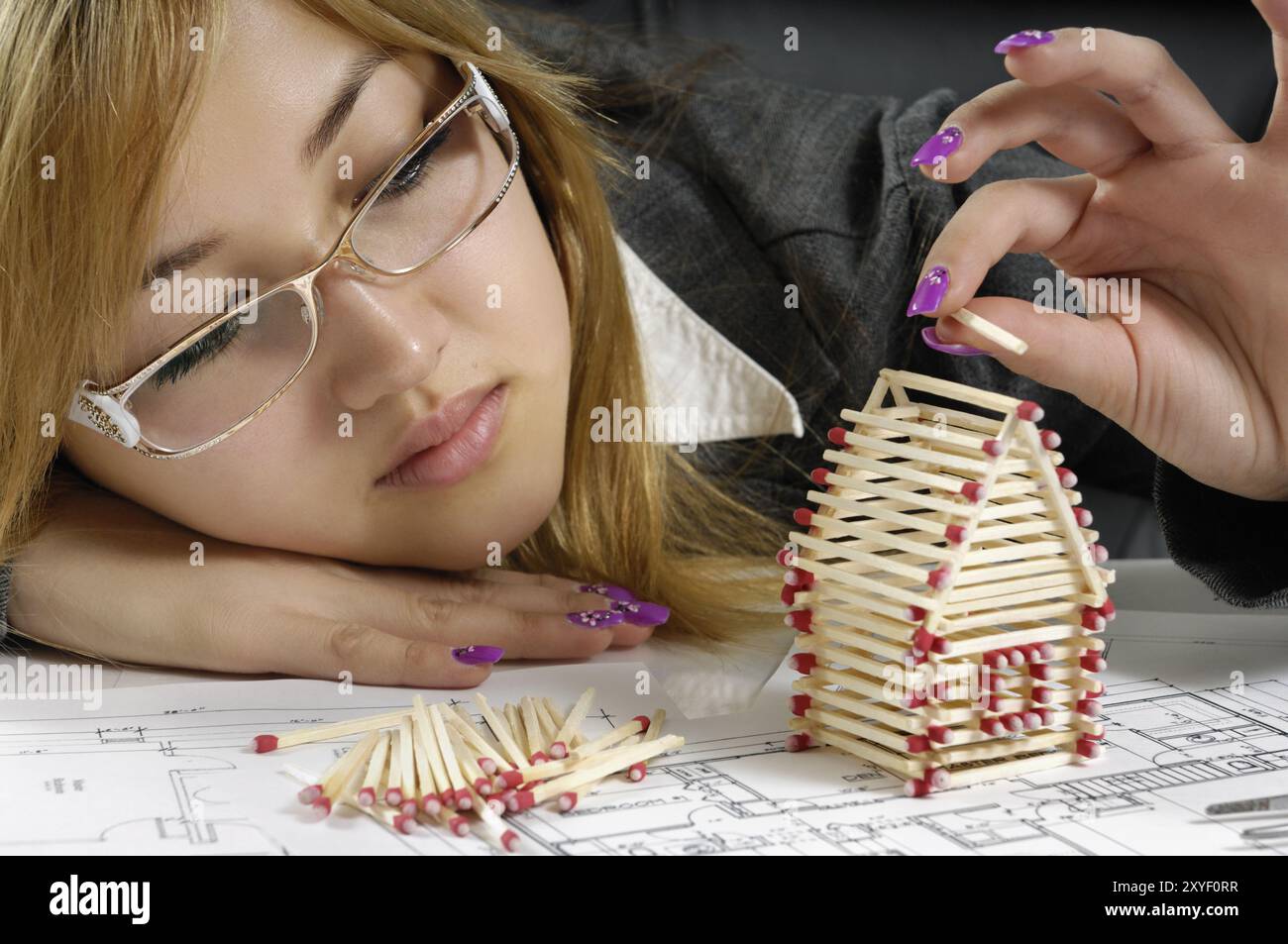 Giovane e attraente donna d'affari che costruisce una casa da partite nel suo ufficio Agenzia immobiliare industria edile ristrutturazione casa Architectu Foto Stock