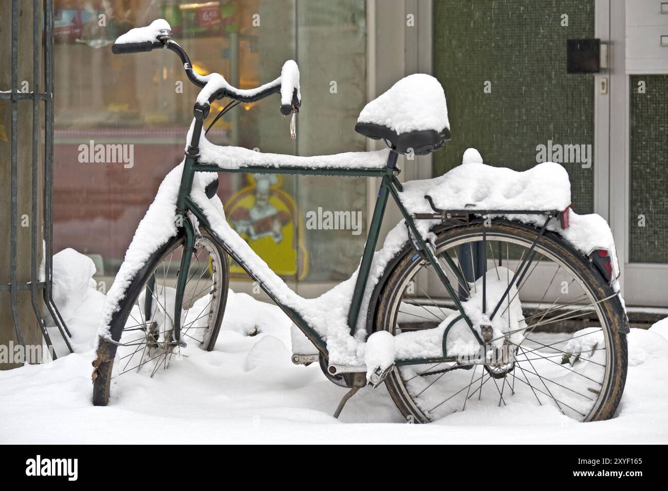 Bicicletta innevata di fronte alla porta d'ingresso Foto Stock