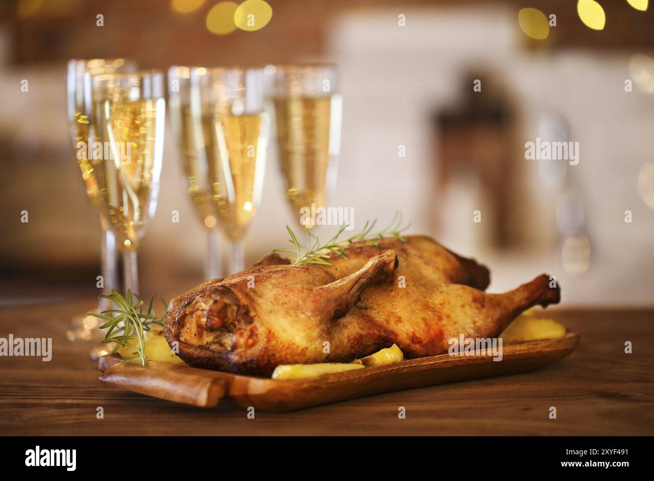 Cena di Natale con anatra arrosto e champagne sul tavolo di legno Foto Stock