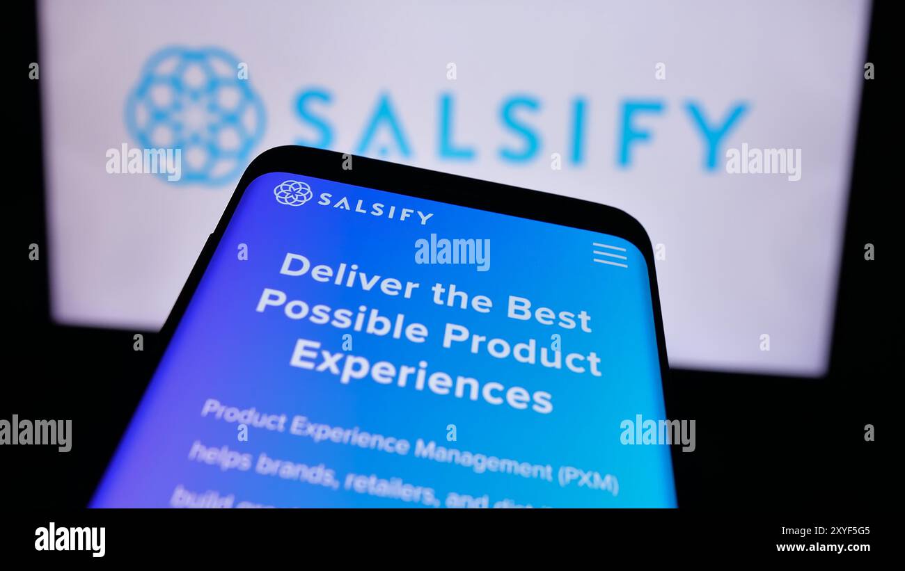 Smartphone con sito Web della società statunitense di gestione dell'esperienza di prodotto Salsify Inc. Davanti al logo aziendale. Mettere a fuoco in alto a sinistra sul display del telefono. Foto Stock