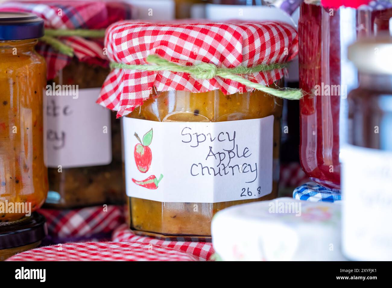 Regno Unito. Chutney di mele speziate fatte in casa conservate in vasetti di vetro, etichettate e rifinite con un topper in tessuto. prodotto con mele da cucina stagionali coltivate in casa Foto Stock