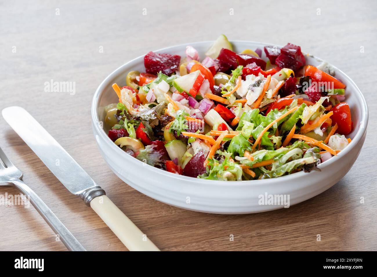 Un'insalata sana della dieta mediterranea servita in una ciotola contenente ingredienti colorati per insalata, tra cui pomodoro peperoni barbabietola e lattuga. Foto Stock