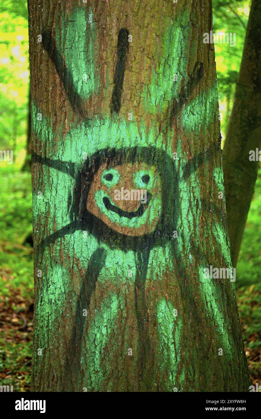 Graffiti, sole ridendo su un tronco d'albero Foto Stock