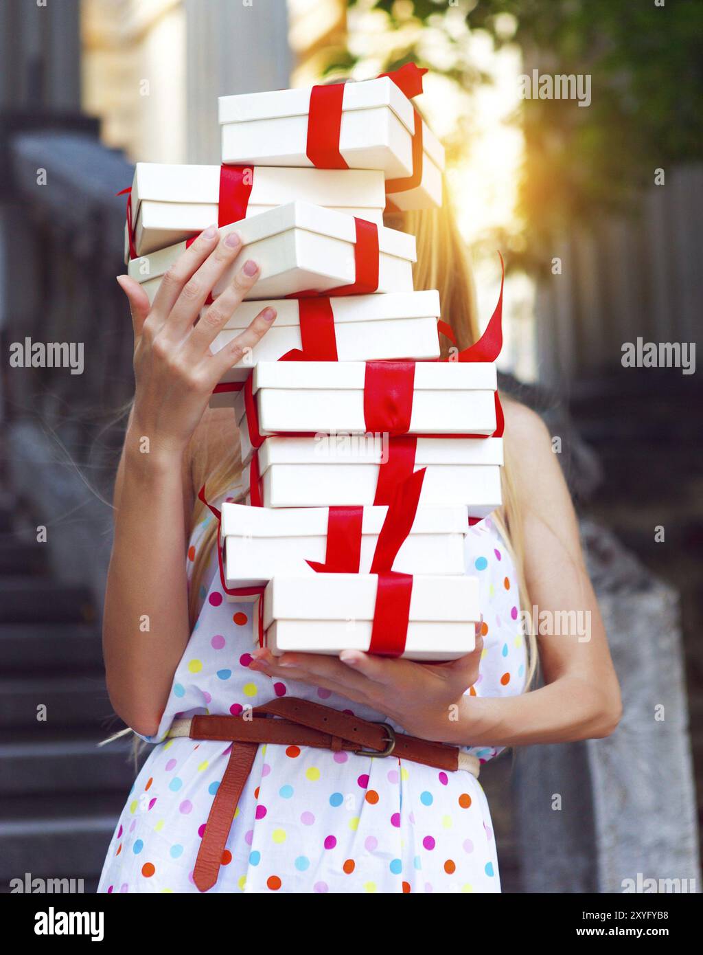 Confezioni regalo nelle mani della giovane donna bionda che indossa la polka dots dress all'aperto Foto Stock