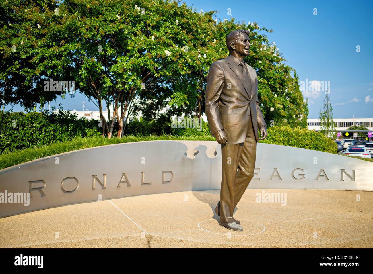 ARLINGTON, Virginia - la statua di Ronald Reagan all'aeroporto nazionale Ronald Reagan di Washington (DCA) commemora il 40° presidente degli Stati Uniti. Creata dal famoso scultore Paul Moore, questa statua in bronzo si erge in modo prominente all'ingresso dell'aeroporto, simboleggiando l'eredità duratura di Reagan e i contributi all'aviazione e alla storia americana. Situato ad Arlington, Virginia, l'aeroporto funge da porta vitale per la capitale della nazione, riflettendo sia il suo significato storico che l'importanza moderna. Foto Stock