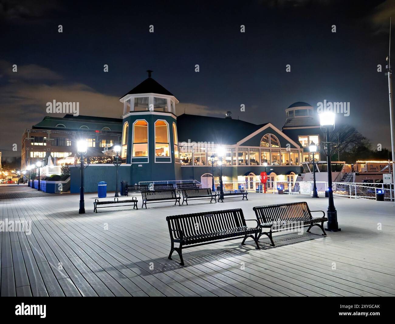 Old Town Alexandria Waterfront at Night Virginia // ALEXANDRIA, Virginia, Stati Uniti — Un molo si estende nel fiume Potomac lungo il lungomare di Old Town Alexandria di notte. L'area storica sul lungomare presenta passaggi illuminati e vedute del fiume. Il lungomare della città vecchia di Alexandria è stato trasformato negli ultimi anni con parchi, ristoranti e spazi pubblici. L'area è una popolare destinazione serale sia per la gente del posto che per i turisti che visitano la regione di Washington DC. Foto Stock