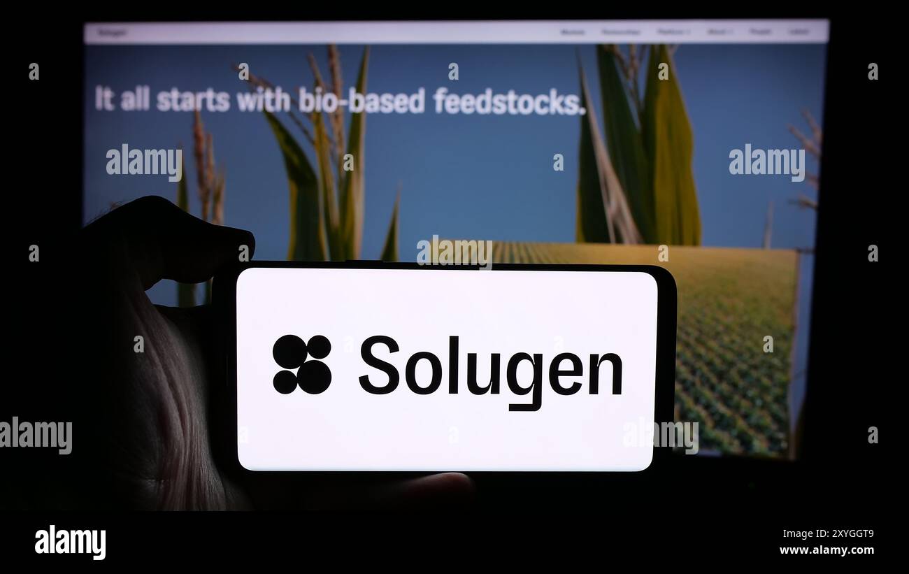 Persona che possiede un telefono cellulare con il logo della società americana di produzione chimica Solugen Inc. Davanti alla pagina Web. Mettere a fuoco il display del telefono. Foto Stock