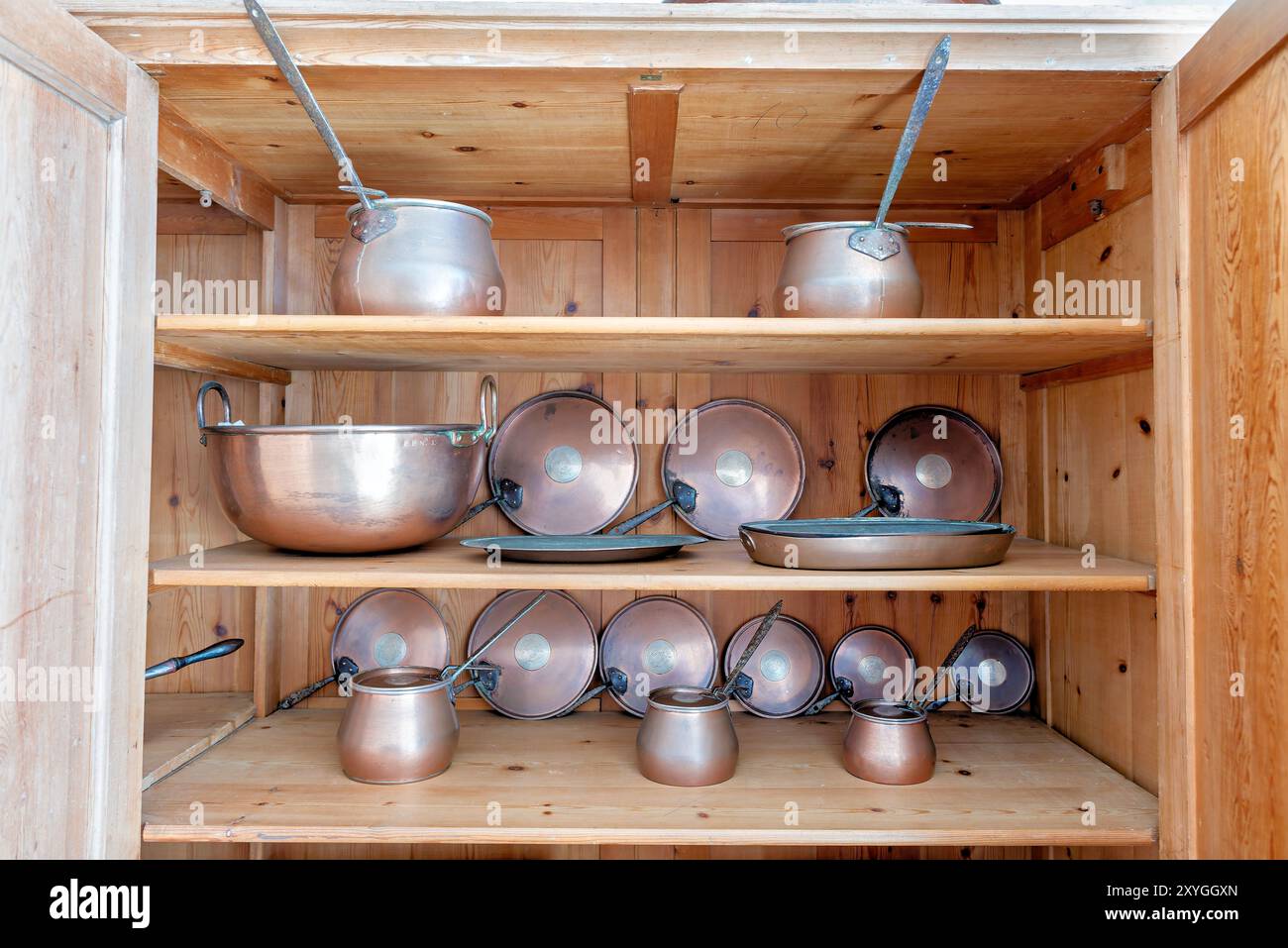 Pentole in rame da cucina di pena Palace Sintra Portugal // SINTRA, Portugal - una serie di pentole e padelle di rame scintillanti esposte nella cucina di pena Palace. Il palazzo romantico del XIX secolo, costruito per re Ferdinando II, presenta cucine d'epoca ben conservate che mostrano l'infrastruttura culinaria necessaria per le operazioni della casa reale. Questi recipienti in rame rappresentano il tipo di pentole di livello professionale comunemente utilizzate nelle cucine aristocratiche dell'epoca. Il Palácio da pena, completato nel 1854, si erge come uno degli esempi più significativi di architettura romantica del Portogallo. Le cucine del palazzo pro Foto Stock