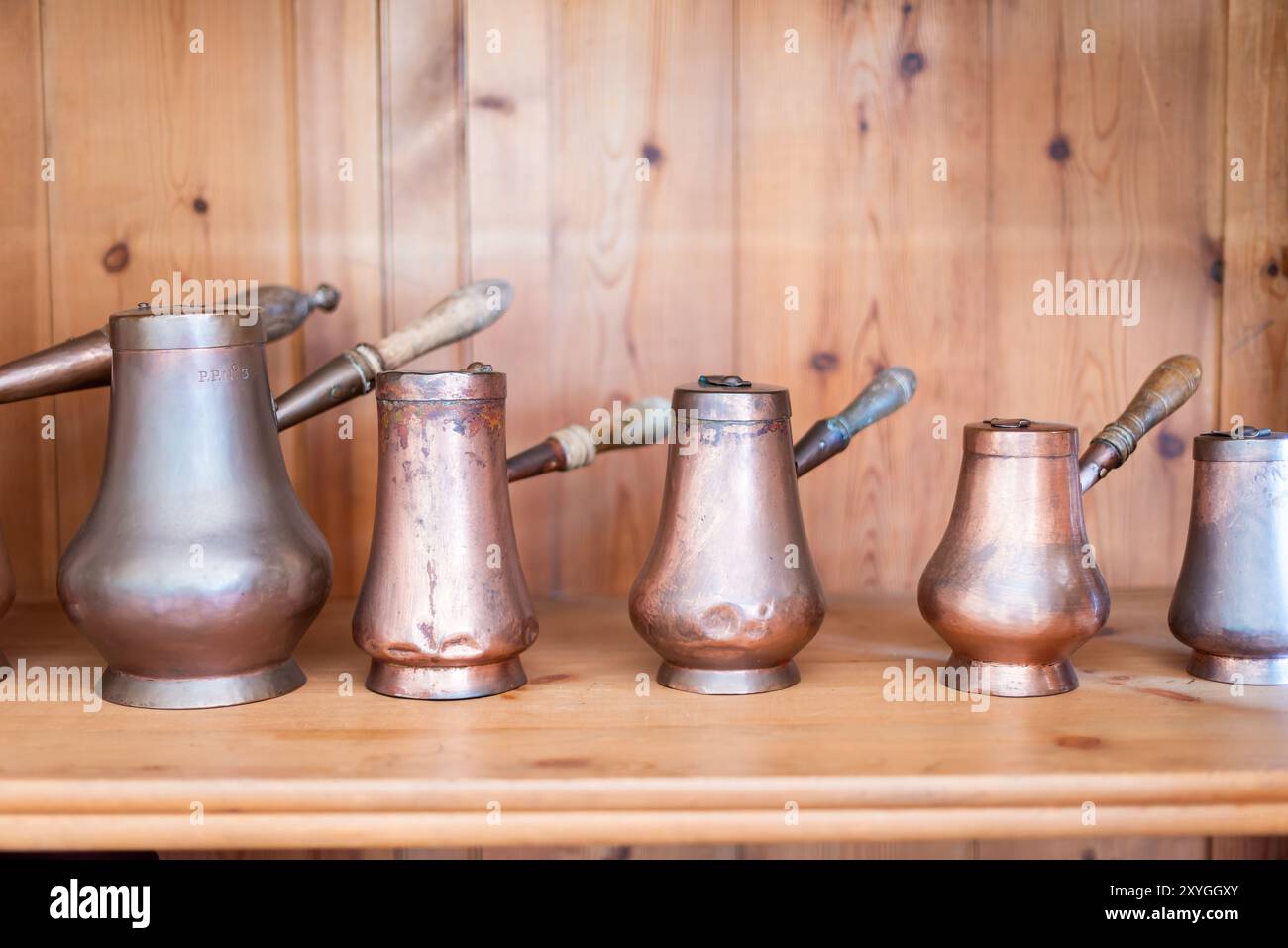 Pentole in rame del Palácio da pena Sintra Portugal // SINTRA, Portugal - una serie di pentole e padelle in rame scintillanti esposte nella cucina del Palácio da pena. Il palazzo romantico del XIX secolo, costruito per re Ferdinando II, presenta cucine d'epoca ben conservate che mostrano l'infrastruttura culinaria necessaria per le operazioni della casa reale. Questi recipienti in rame rappresentano il tipo di pentole di livello professionale comunemente utilizzate nelle cucine aristocratiche dell'epoca. Il Palácio da pena, completato nel 1854, si erge come uno degli esempi più significativi di architettura romantica del Portogallo. Le cucine del palazzo forniscono in Foto Stock