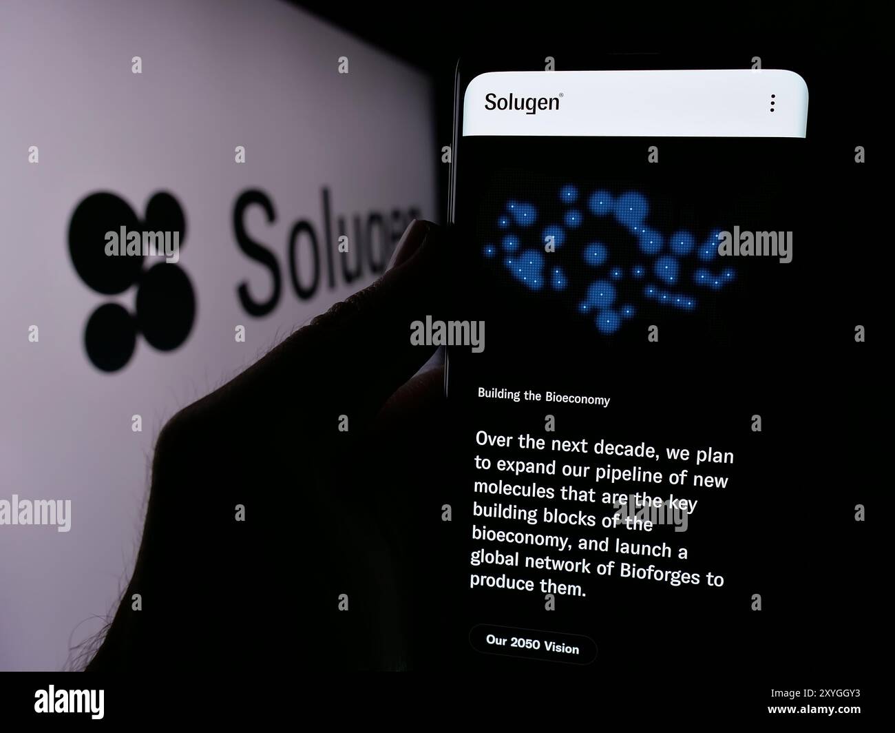 Persona che detiene un cellulare con la pagina web della società di produzione chimica statunitense Solugen Inc. Davanti al logo. Messa a fuoco al centro del display del telefono. Foto Stock