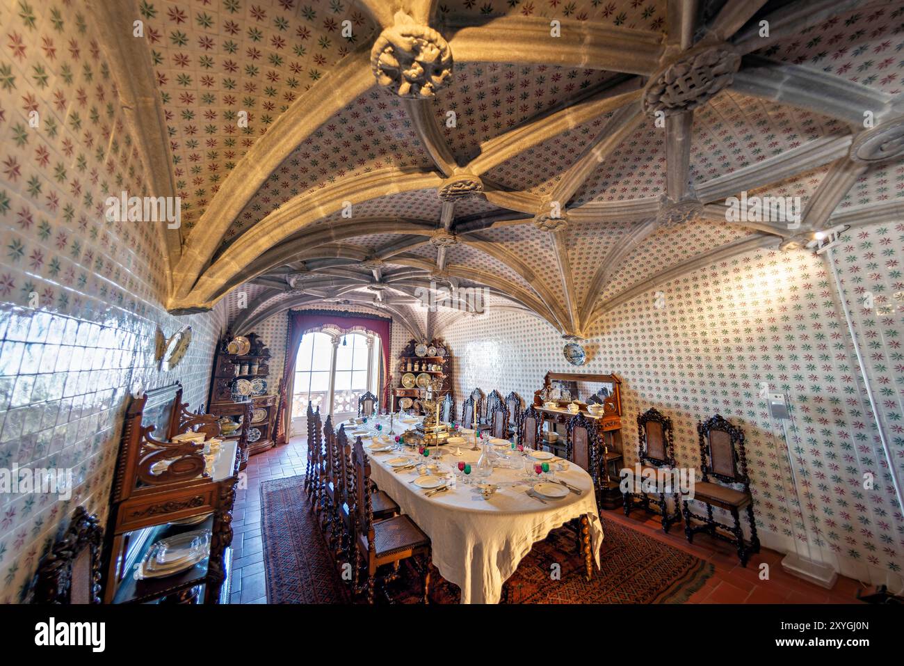 SINTRA, Portogallo: La sala da pranzo del Palácio da pena, ex refettorio dei monaci geronimiti, convertita da re Ferdinando II nella sala da pranzo privata della famiglia reale portoghese. La sala presenta archi a volta a costola manuelina del XVI secolo ed è rivestita con piastrelle del XIX secolo di Fábrica Roseira. I mobili in quercia, commissionati da re Ferdinando II nel 1866 da Casa Barbosa e Costa, aggiungono un tocco storico e regale all'ambiente dello spazio. Foto Stock