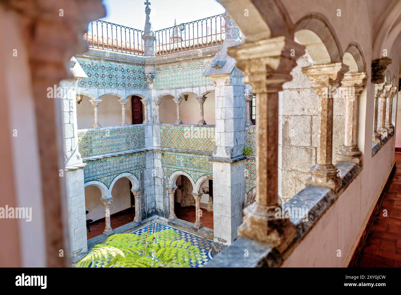 Palazzo pena Manueline Chiostro Sintra Portogallo // SINTRA, Portogallo — il Chiostro Manueline a Palácio pena, originariamente costruito nel 1511, presenta due piani con pareti adornate con piastrelle ispano-moresche del XVI secolo. Durante la conversione del monastero in un palazzo reale, gli archi del chiostro furono chiusi con finestre, che furono poi rimosse negli anni '1930 Le gallerie del chiostro, un tempo parte del monastero di Hieronymite, ora fungono da corridoi che collegano diverse sezioni del palazzo. Lo stile architettonico rappresenta il periodo manuelino portoghese, caratterizzato da ornati Foto Stock