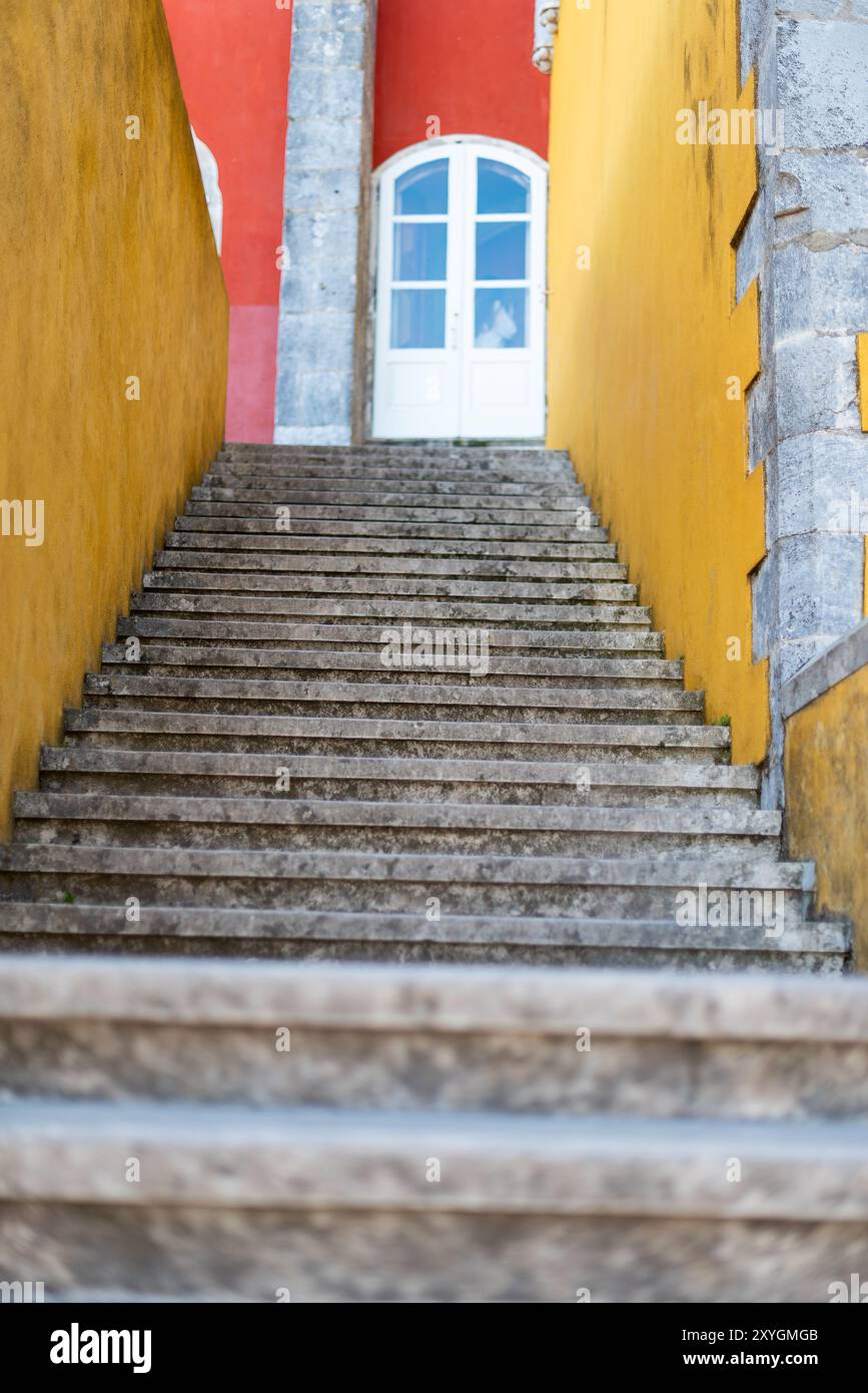 Scala di pietra del Palácio da pena Sintra Portogallo // SINTRA, Portogallo - Una scalinata di pietra al Palácio da pena, un importante punto di riferimento architettonico a Sintra, Portogallo. Il palazzo è rinomato per la sua architettura romanticista ed è un sito patrimonio dell'umanità dell'UNESCO. La scalinata è una delle tante che conducono i visitatori attraverso i vasti giardini del palazzo, che mescolano influenze architettoniche gotiche, moresche e rinascimentali. Foto Stock