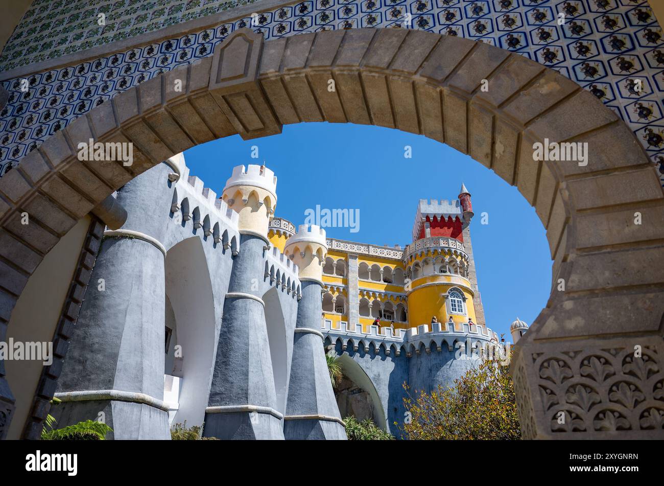 Architettura esterna del Palácio da pena Sintra Portogallo // SINTRA, Portogallo - l'architettura esterna vibrante ed eclettica del Palácio da pena, che mostra la sua miscela di stili romanticisti, moreschi e neo-manuelini. Costruito nel XIX secolo come residenza estiva per la famiglia reale portoghese, il palazzo fu commissionato da re Ferdinando II e completato nel 1854. Le facciate colorate, i dettagli ornati e gli elementi stravaganti incarnano l'architettura romantica e la visione di re Ferdinando II di un castello da favola. Situato in cima ai Monti Sintra, il palazzo fa parte del paesaggio culturale di Sintra, de Foto Stock