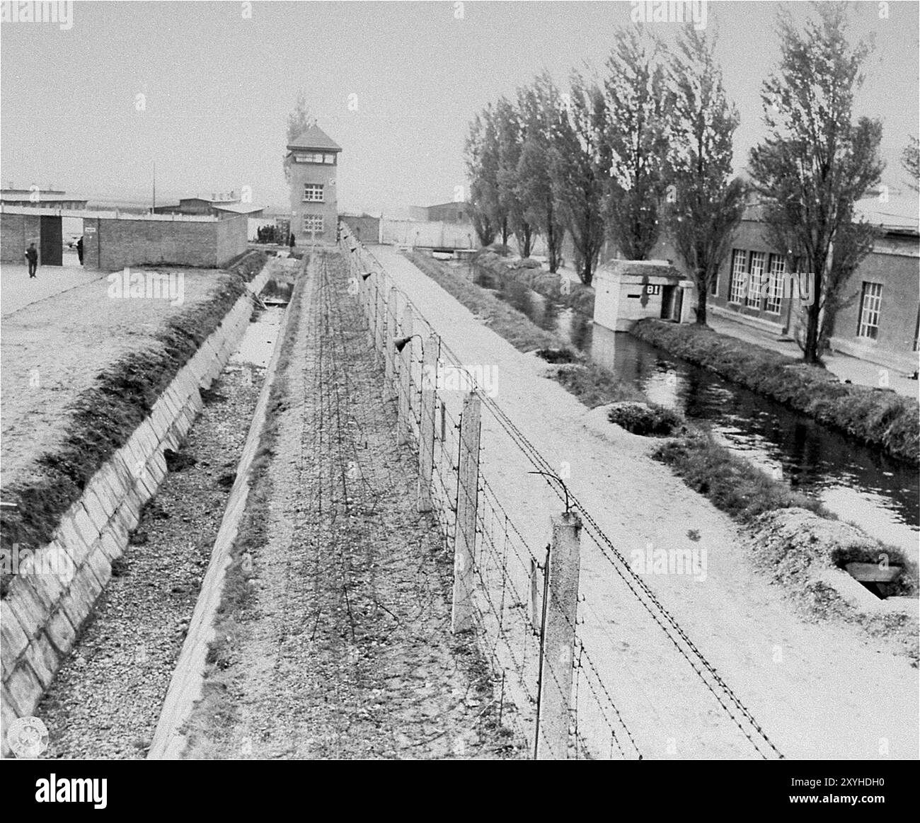 Una veduta della recinzione elettrica, del fossato e delle torri di guardia di Dachau. Dachau fu il primo campo di concentramento nazista, aperto il 22 marzo 1933 (solo 7 settimane dopo l'ascesa al potere di Hitler). Anche se era un campo di lavoro forzato e non c'erano camere a gas lì, la brutalità e le punizioni violente erano la norma. Ci sono stati 32000 morti documentate lì e molte altre migliaia non documentate. Il campo principale (Dachau aveva 100 sottocampi) fu liberato dall'esercito americano il 29 aprile 1945. Foto Stock