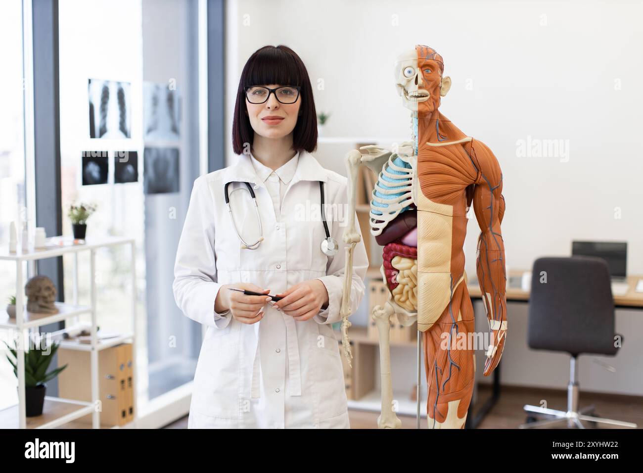 Medico in piedi accanto al modello anatomico in studio medico Foto Stock